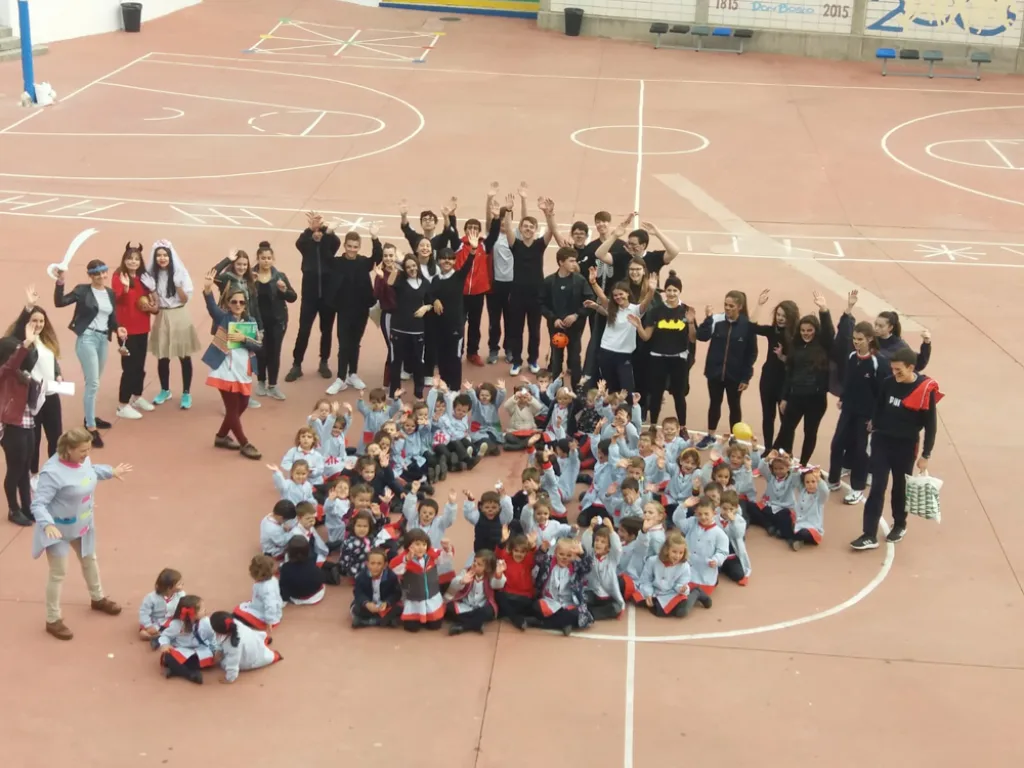Von oben fotografiert: Kinder bilden auf dem Schulhof gemeinsam ein Zeichen.